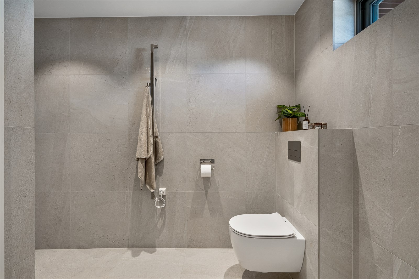 Innredningen består av nedfelt servant i stilren baderomsinnredning, speil med belysning, vegghengt klosett og romslig dusjnisje. Galleribilde