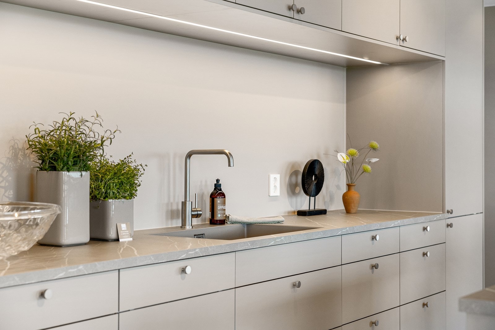 De glatte, stilrene frontene gir et ryddig og eksklusivt inntrykk, og den flotte benkeplaten i laminat gir både god arbeidsflate og en behagelig kontrast til innredningen. Galleribilde