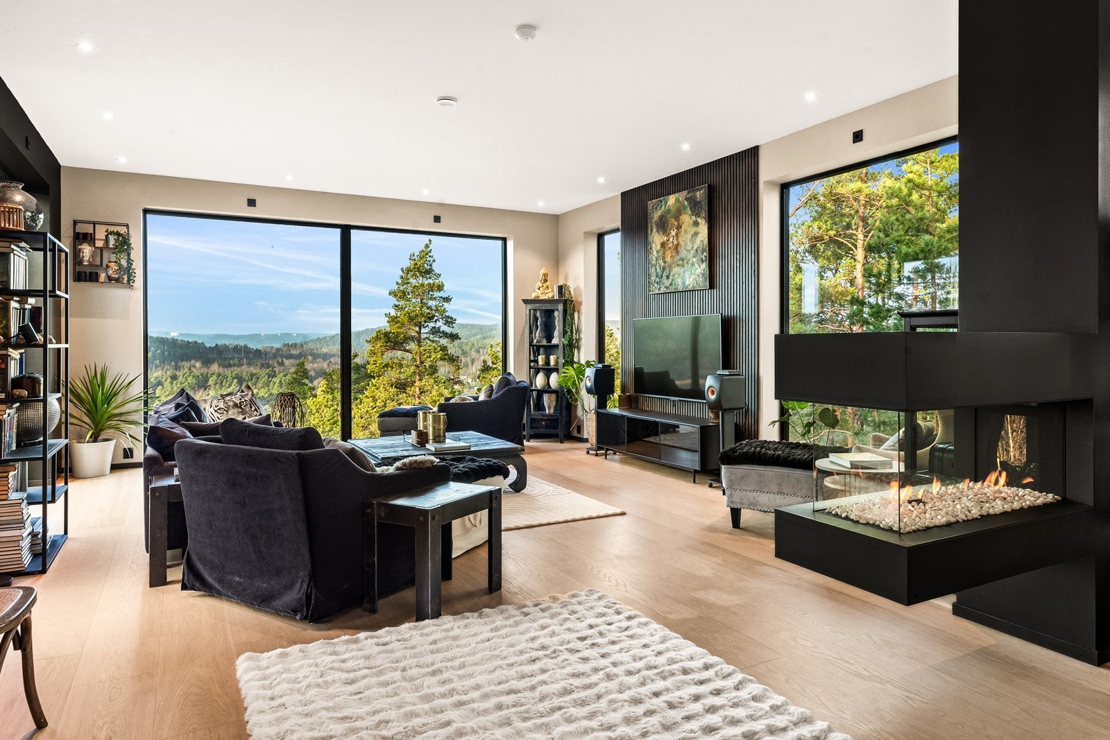 Lys og åpen dagligstue som er adskilt fra spisestue med en moderne gasspeis Galleribilde