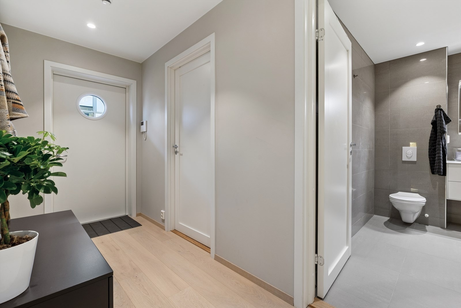 Leiligheten har et helflislagt bad med stilren og moderne innredning. Vannbåren gulvvarme gir behagelig komfort året rundt, og rommet er utformet som en kombinert løsning med både bad og vaskerom - praktisk og funksjonelt for en effektiv hverdag. Galleribilde