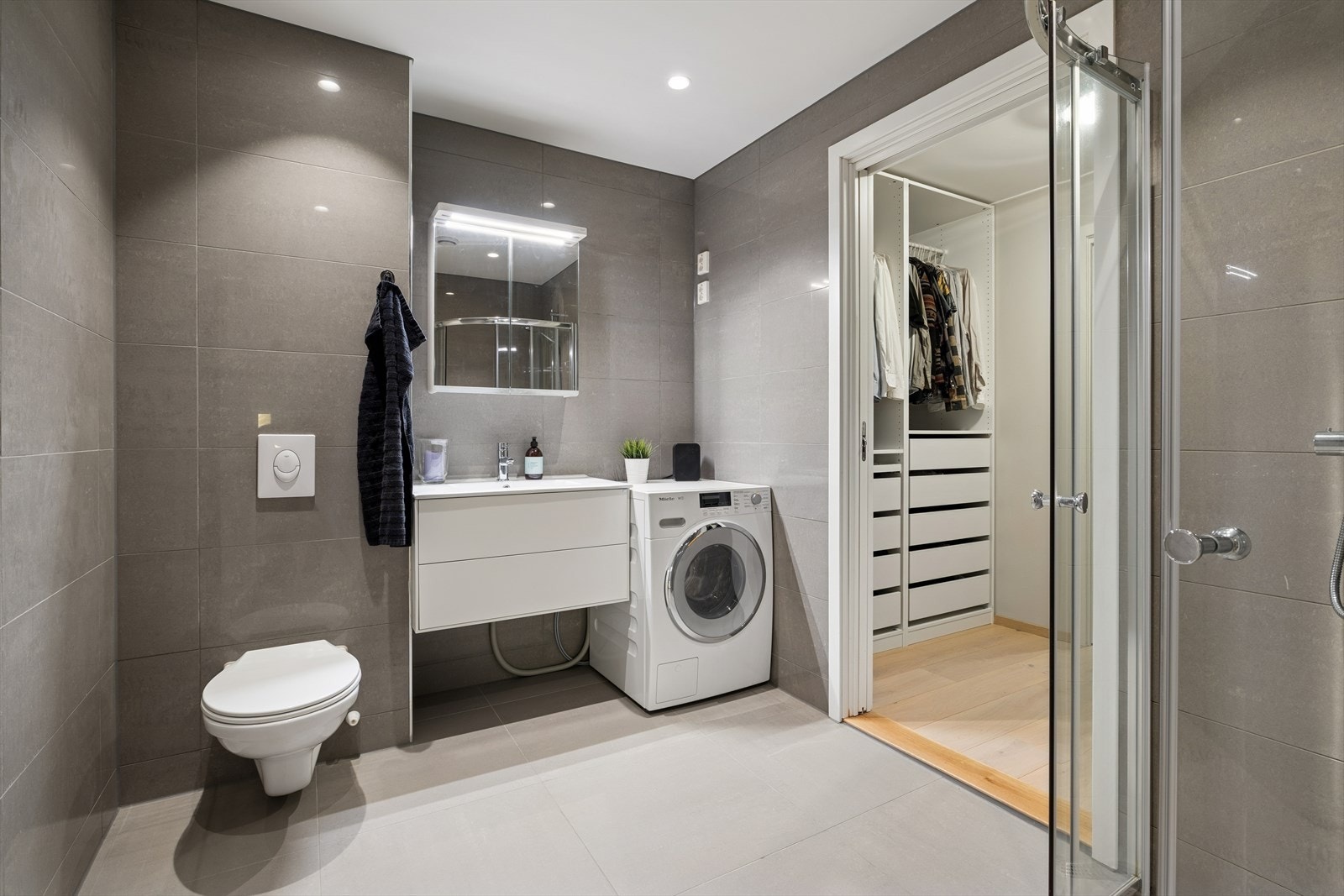 Badet er fra byggeåret 2018 og fremstår som elegant og funksjonelt. Vannbåren gulvvarme, som gir en behagelig temperatur året rundt. Fra badet er det direkte tilgang til et praktisk garderoberom, som igjen leder inn til boligens hovedsoverommet. Galleribilde