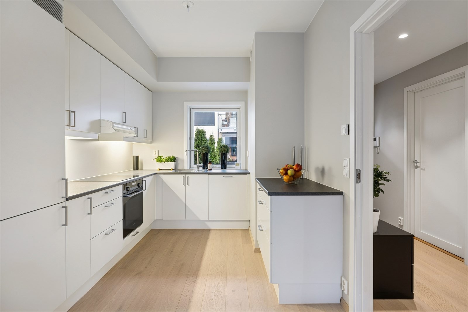 Kjøkkenet er stilrent og praktisk utformet med laminatbenkeplate og planlimt kum som gir et elegant og helhetlig uttrykk. Lys under overskapene skaper både god arbeidsbelysning og en hyggelig atmosfære. Galleribilde