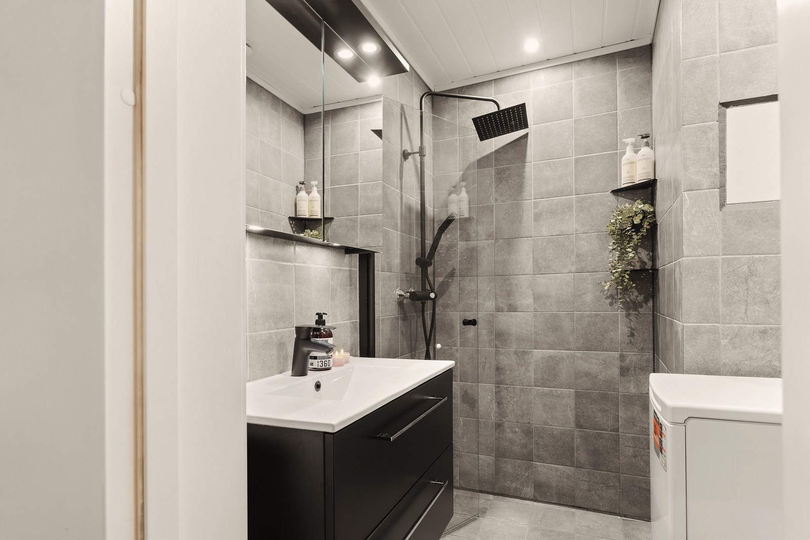 Delikat baderom fra 2021 med flislagt gulv med varmekabler og flislagte vegger. Nedsenket himling med downlights gir et moderne uttrykk. Galleribilde