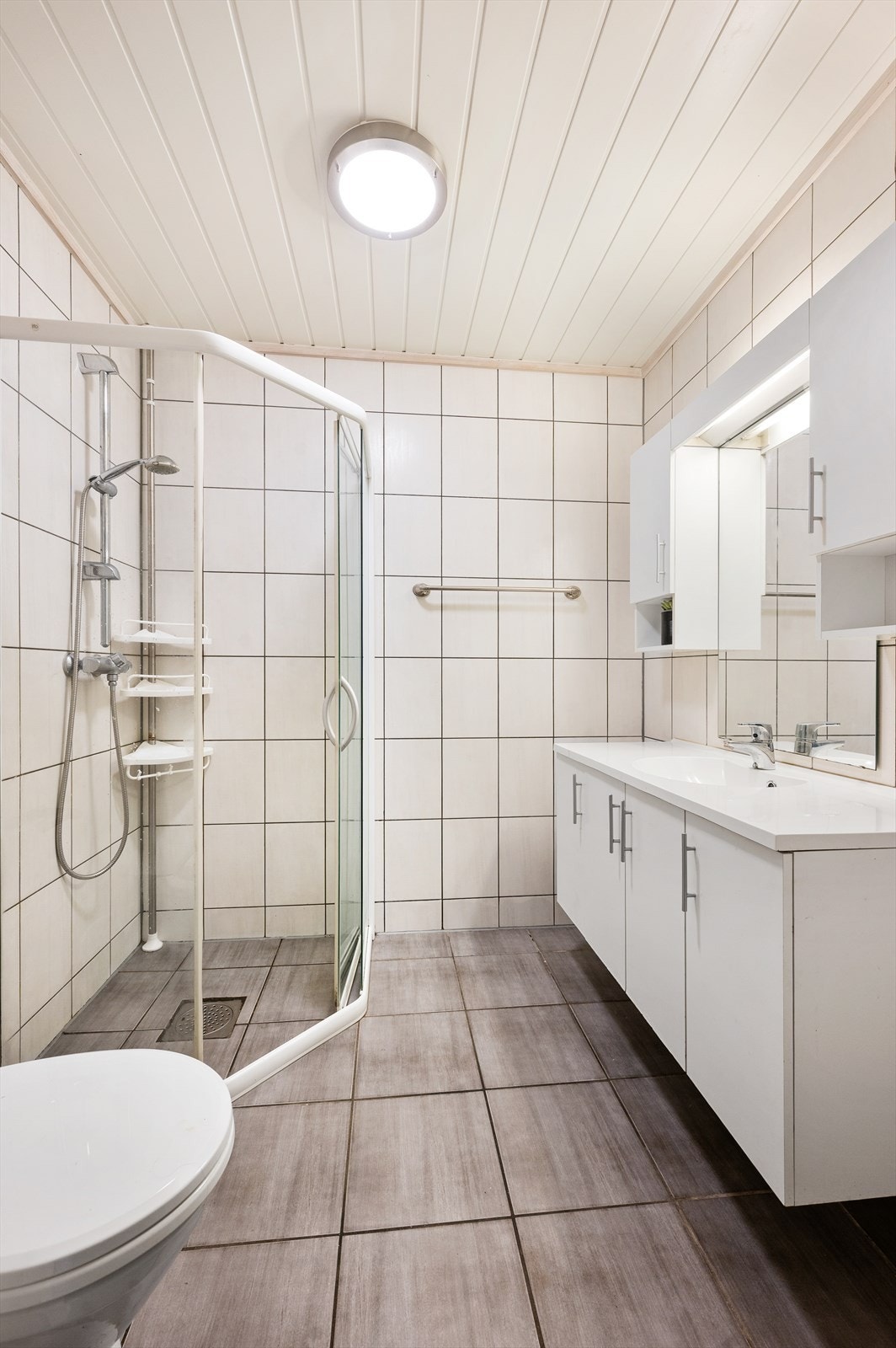 Bad/wc - baderomsinnredning med heldekkende servant, dusjhjørne, klosett og avtrekk. Varmekabler i gulv. Galleribilde