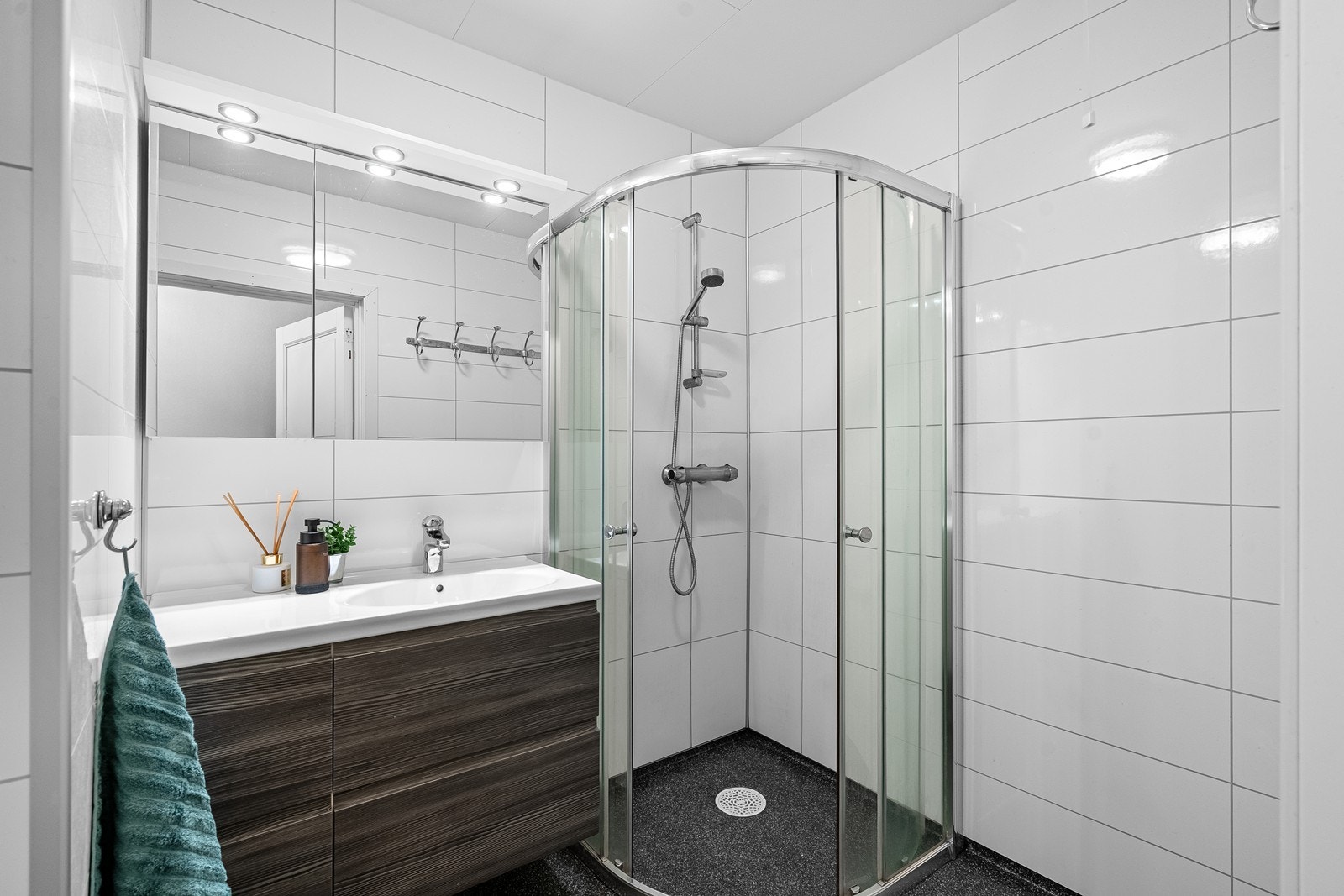 Bad er innredet med vask i seksjon, dusjhjørne og skap for oppbevaring. Galleribilde