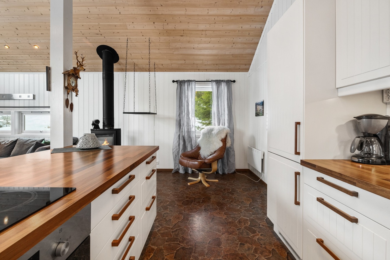 Pent hyttekjøkken med lyse, profilerte fronter og mørk laminert benkeplate Galleribilde