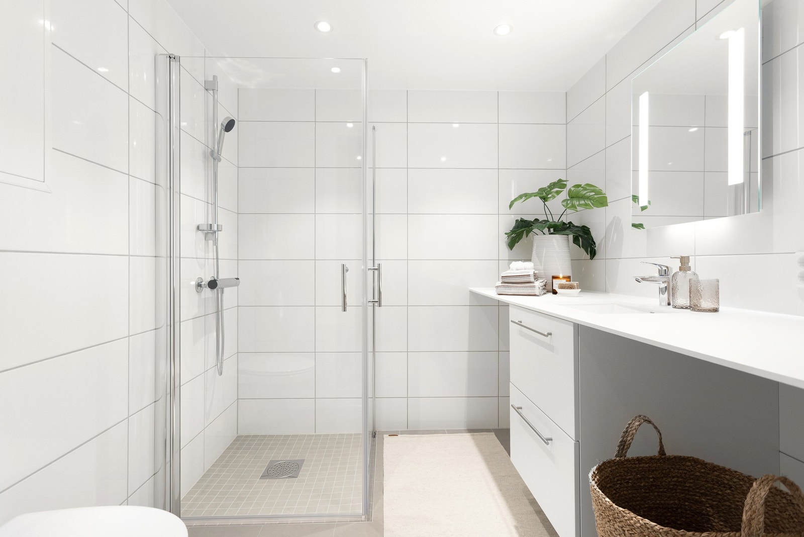 Baderommet er moderne og tidsriktig utstyrt med vegghengt wc, innfellbare glassdører og nisjer til tørketrommel og vaskemaskin. Galleribilde