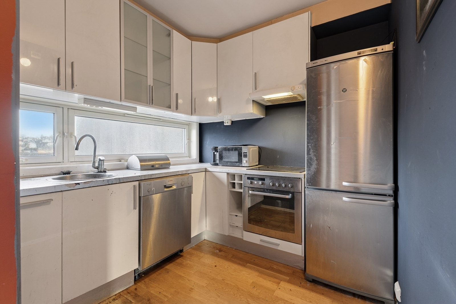 Kjøkkenet ligger i delvis åpen løsning og har en tidløs innredning med hvite glatte fronter - Videre er det laminert benkeplate med nedfelt kjøkkenvask Galleribilde