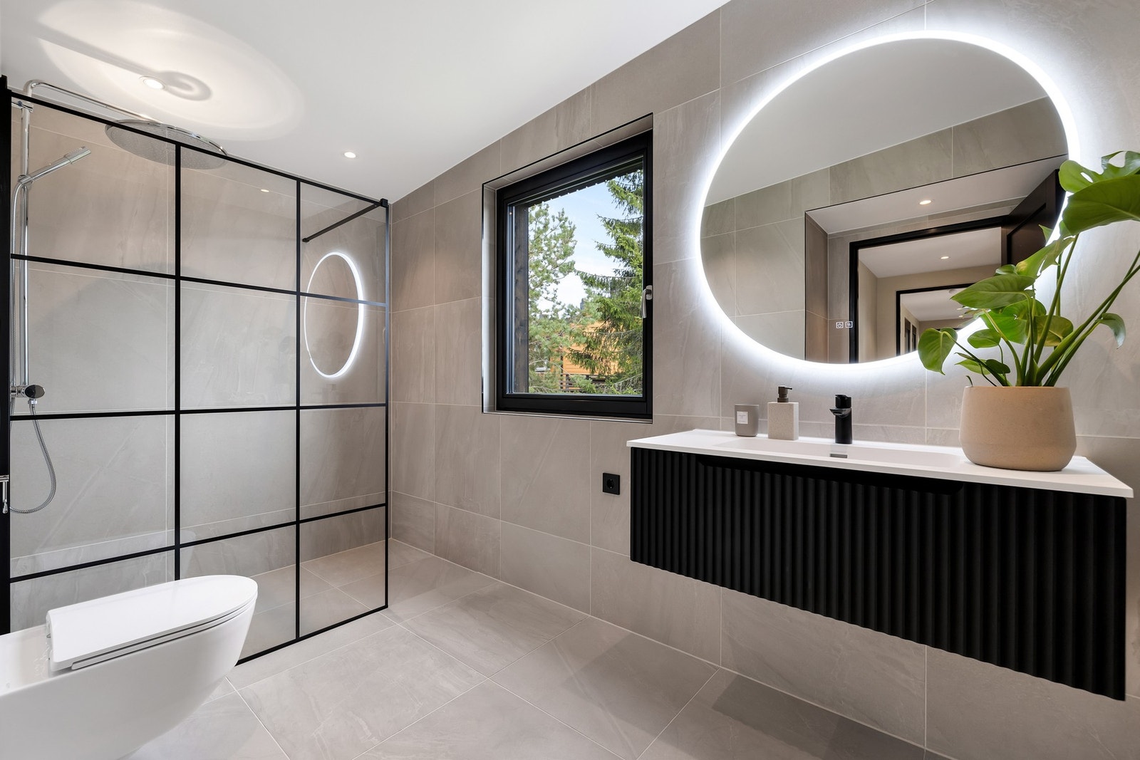 Innbydende baderom med fine 60x60 flis over lun gulvvarme. Dekorativ glassvegg og speil med lys og antiduggfunksjon. Galleribilde