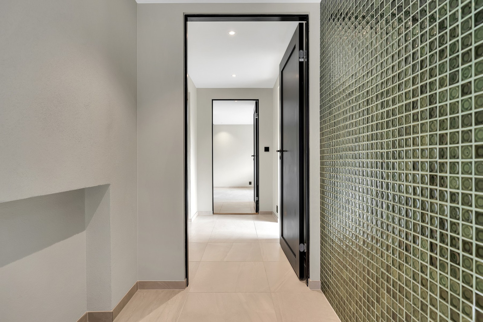 Mellomgang med flislagt gulv og varmekabler samt dekorative flis på veggen. Galleribilde