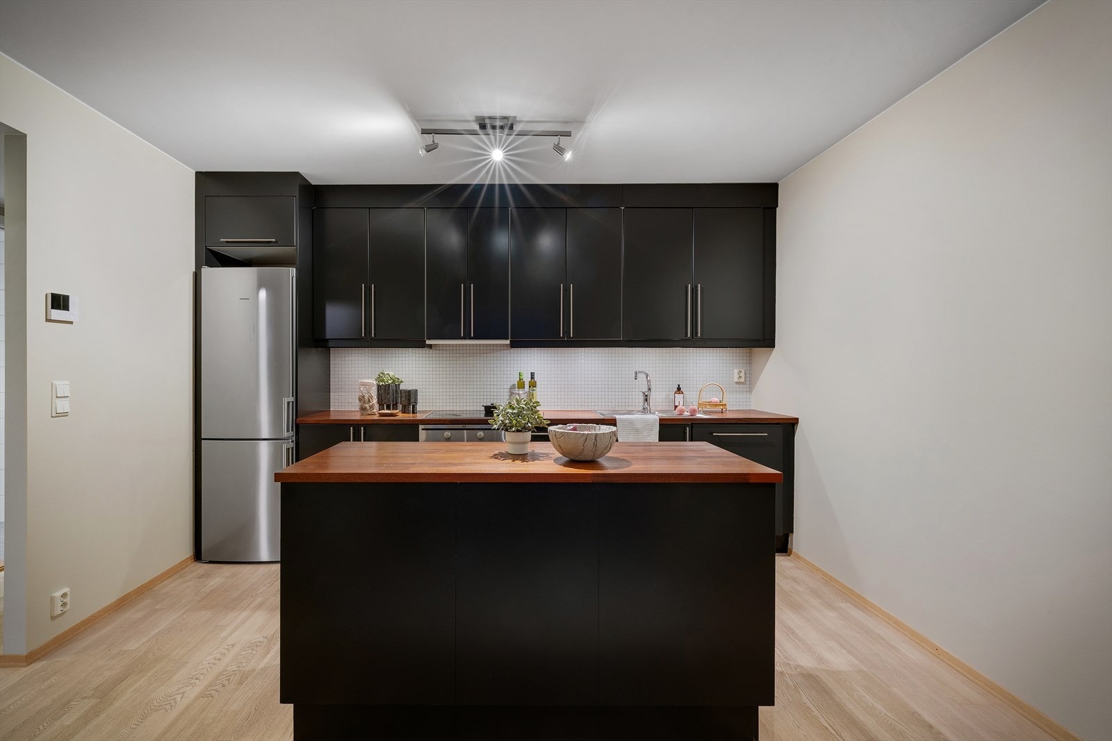 Stilfullt kjøkken med glatte svarte fronter, benkeplate med nedfelt vask og platetopp Galleribilde