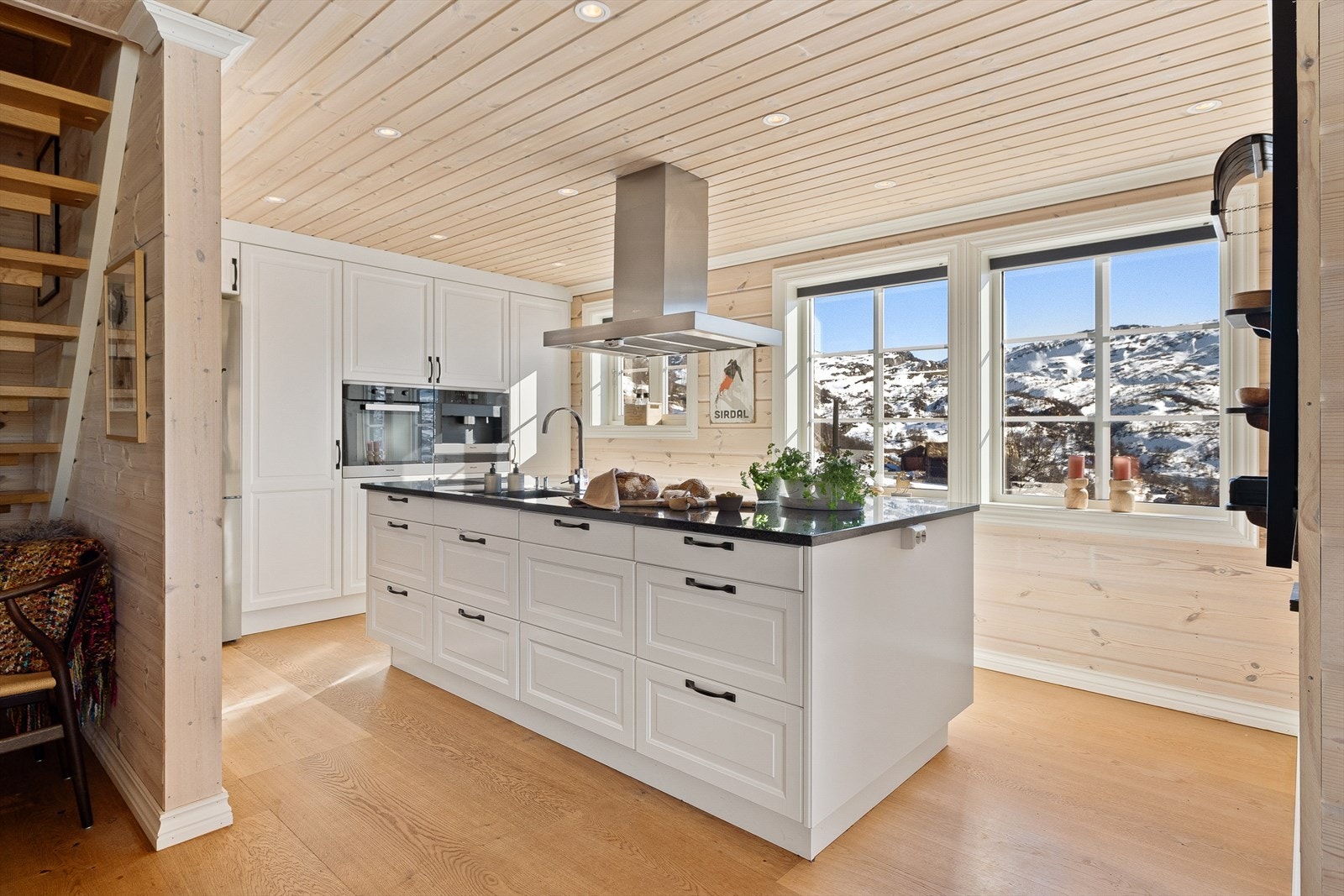 Flott klassisk hvitt kjøkken med benkeplate i stein. Integrerte hvitevarer. Kaffemaskin og stekeovn fra Miele. Galleribilde