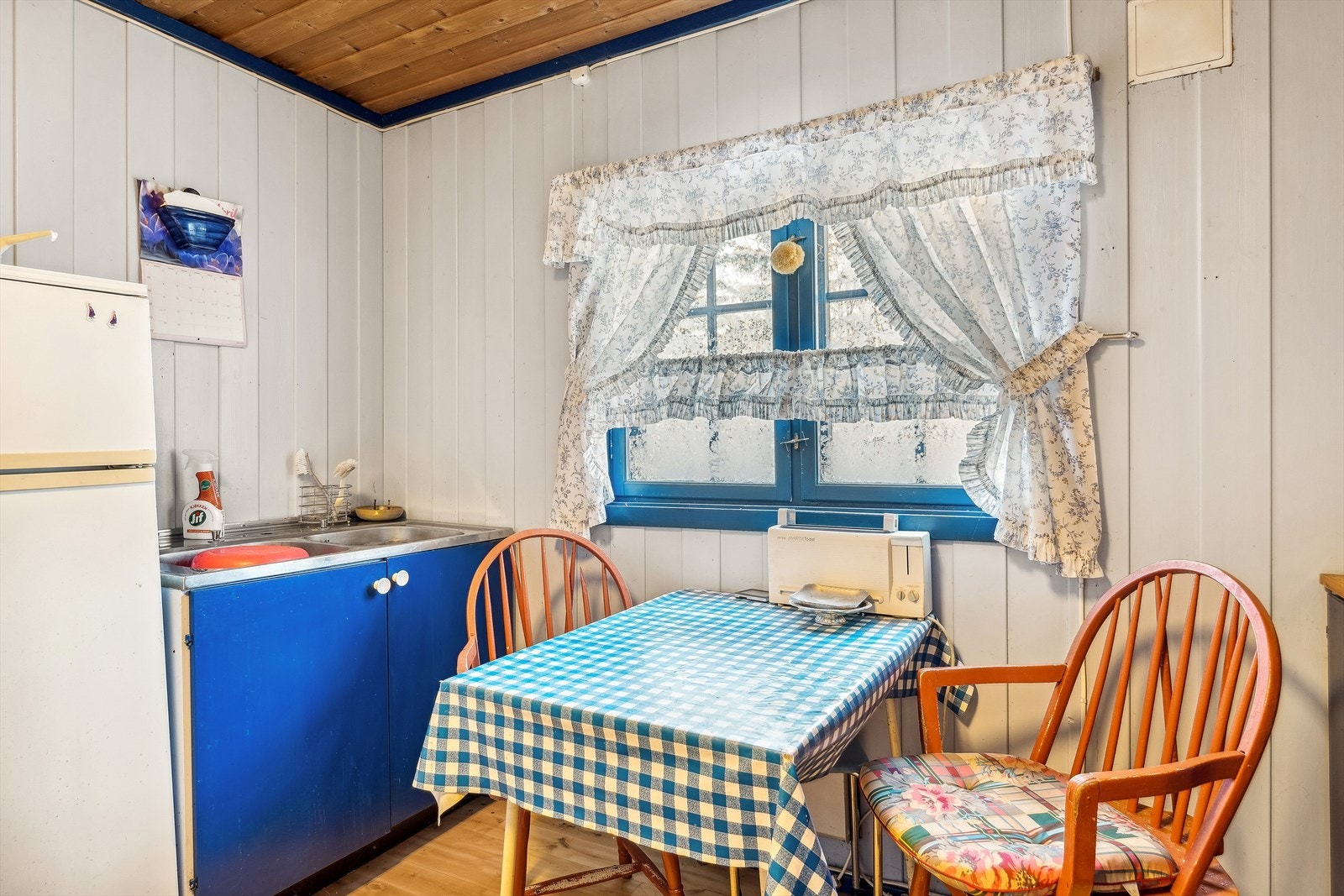 Kjøkkenet har eldre innredning med malte, glatte fronter, og benkeplate av laminat. Galleribilde