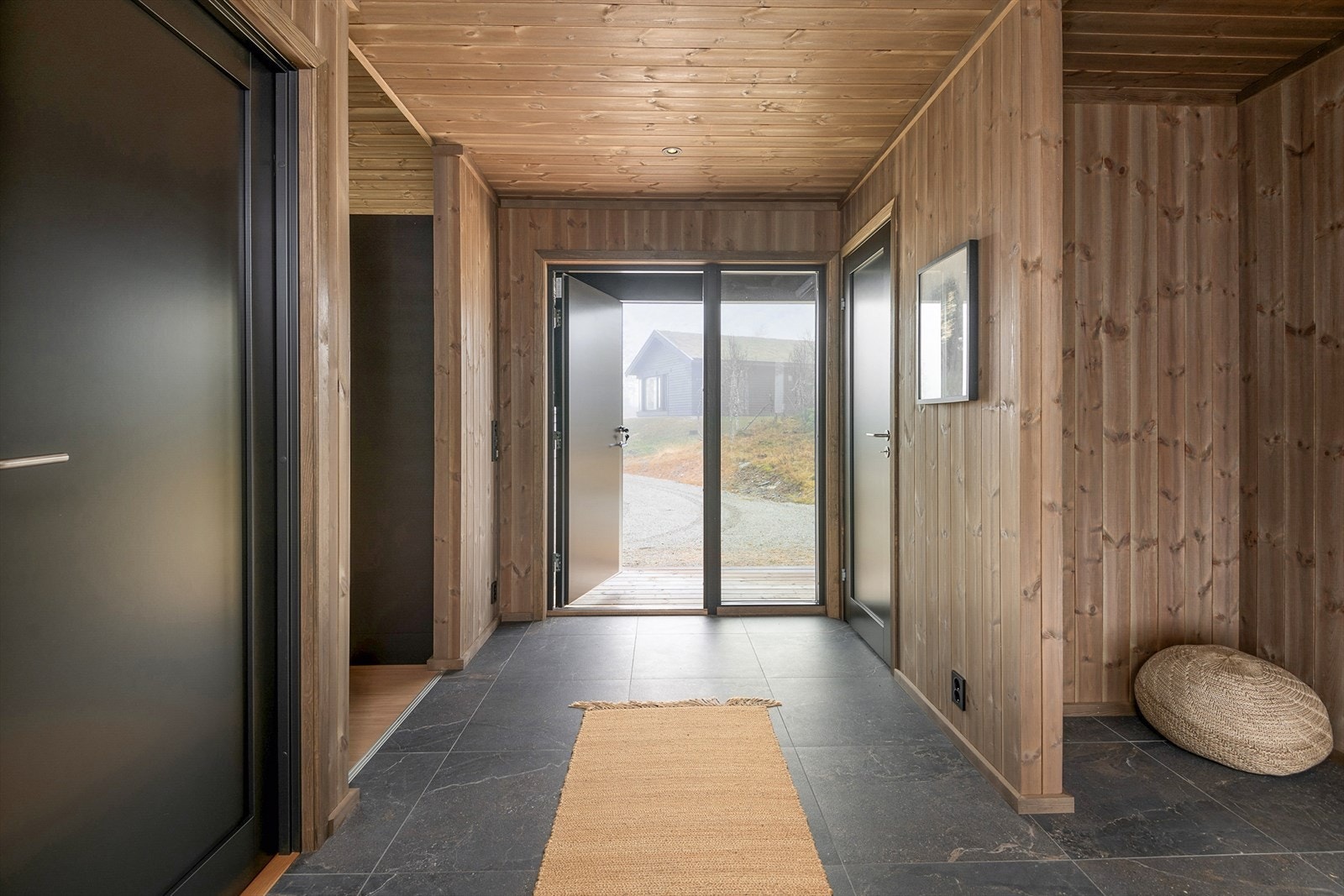 Lys og innbydende entré med moderne detaljer. Perfekt for å ønske gjester velkommen. Et flott førsteinntrykk av boligen. Illustrasjonsbilde fra Svartskardvegen 66. Denne hytta er speilvendt i forhold til avbildet hytte. Galleribilde