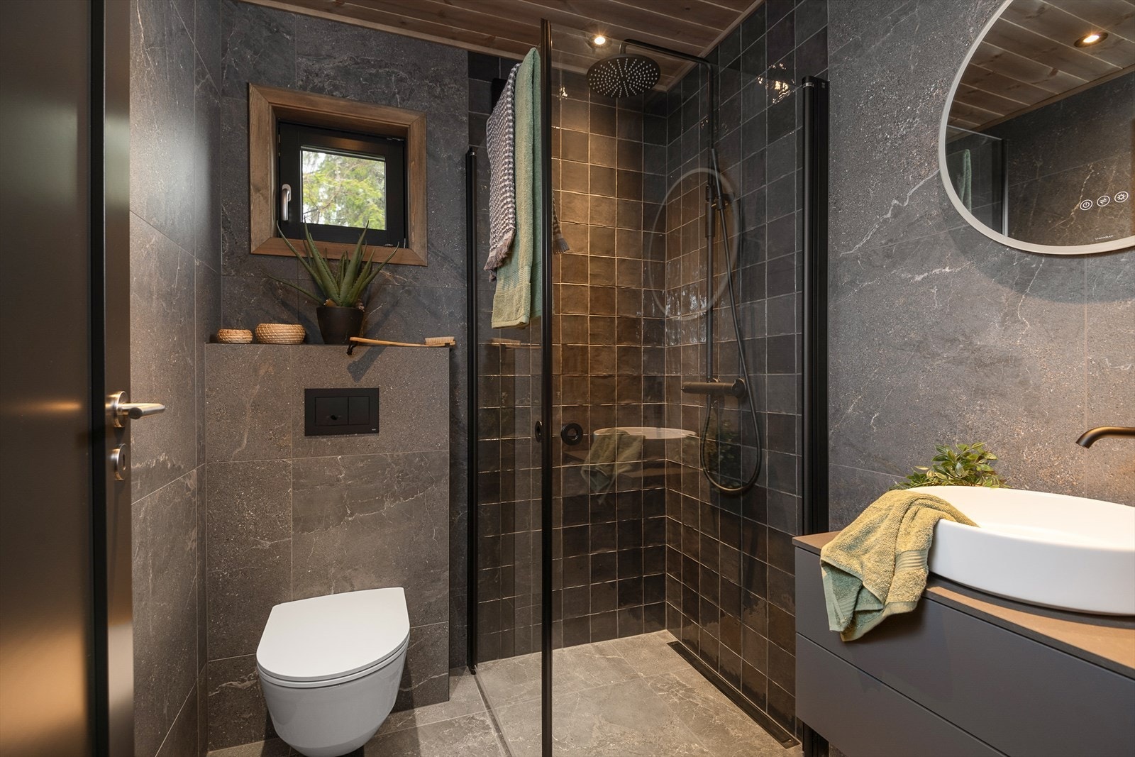 Hyttas andre bad er i samme, delikate og gjennomførte stil. Fin effekt med mosaikkfliser i dusjhjørnet. I tillegg servantinnredning og vegghengt WC. Smakfulle fargevalg. Galleribilde