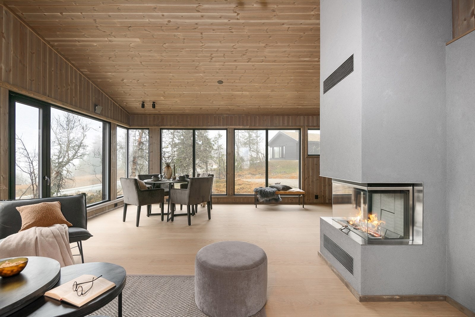 Lys og romslig stue med store vinduer og peis. Naturskjønn utsikt som skaper en fredelig atmosfære året rundt. Illustrasjonsbilde fra Svartskardvegen 66. Denne hytta er speilvendt i forhold til avbildet hytte. Galleribilde