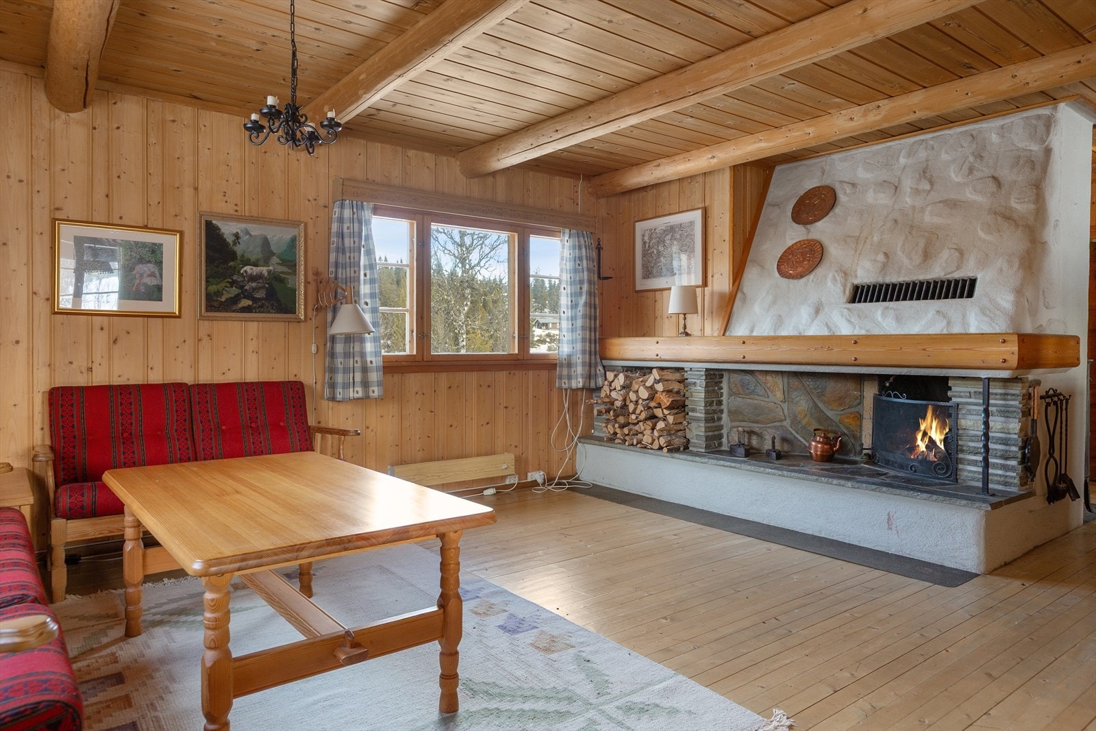 Inne i hytta er det enn lys og luftig stue med trehvite vegger og tømmeråser i flat himling gir et fint hyttepreg. Peisen strekker seg helt opp til himlingen, og gir et flott innsyn til peisflammene. Galleribilde