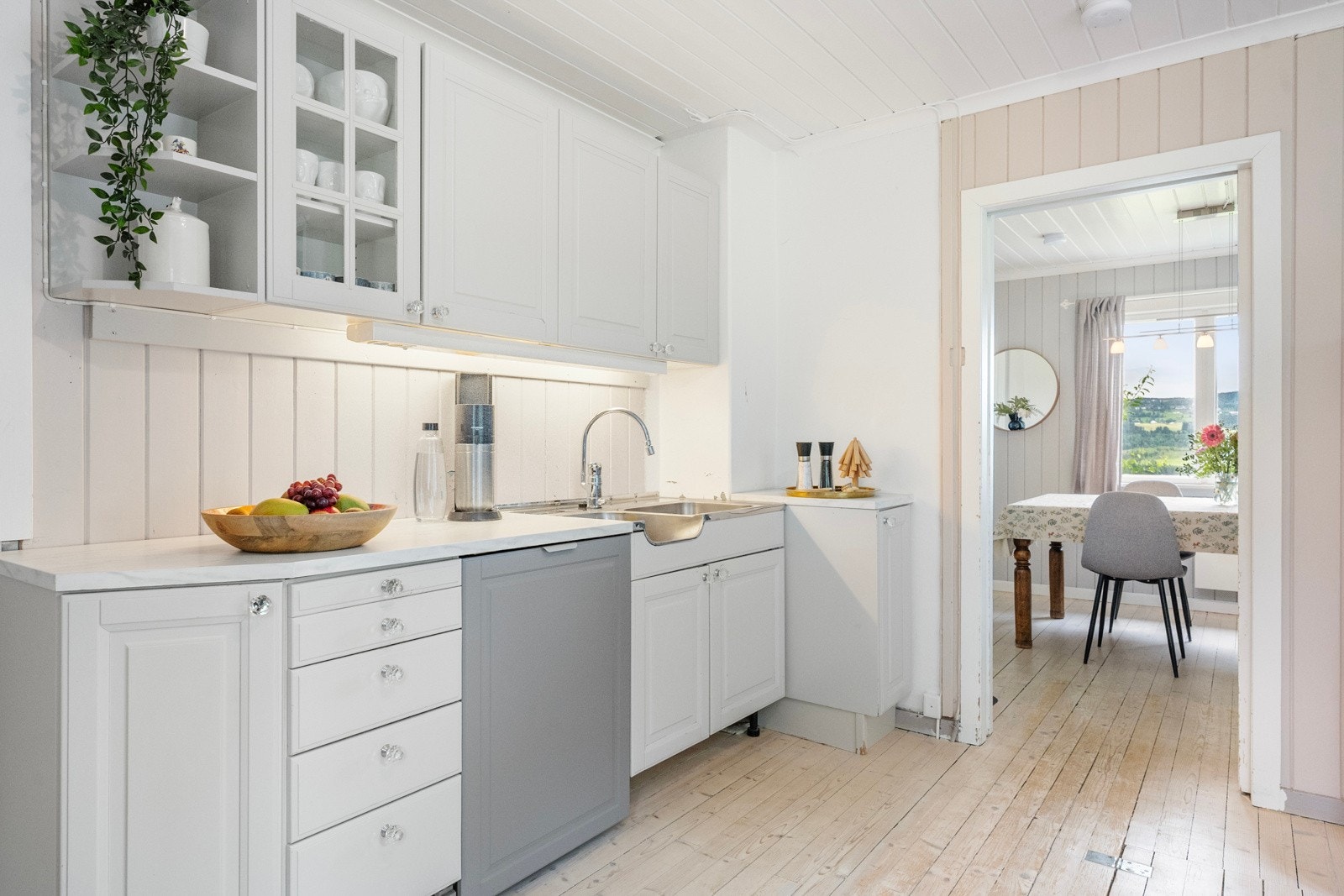 Kjøkkeninnredningen har profilerte fronter, enkelte av frontene har glass. Laminat benkeplate, det er malt panel mellom over, og underskap. Vask i rustfritt stål med 1-greps kjøkkenarmatur. Galleribilde