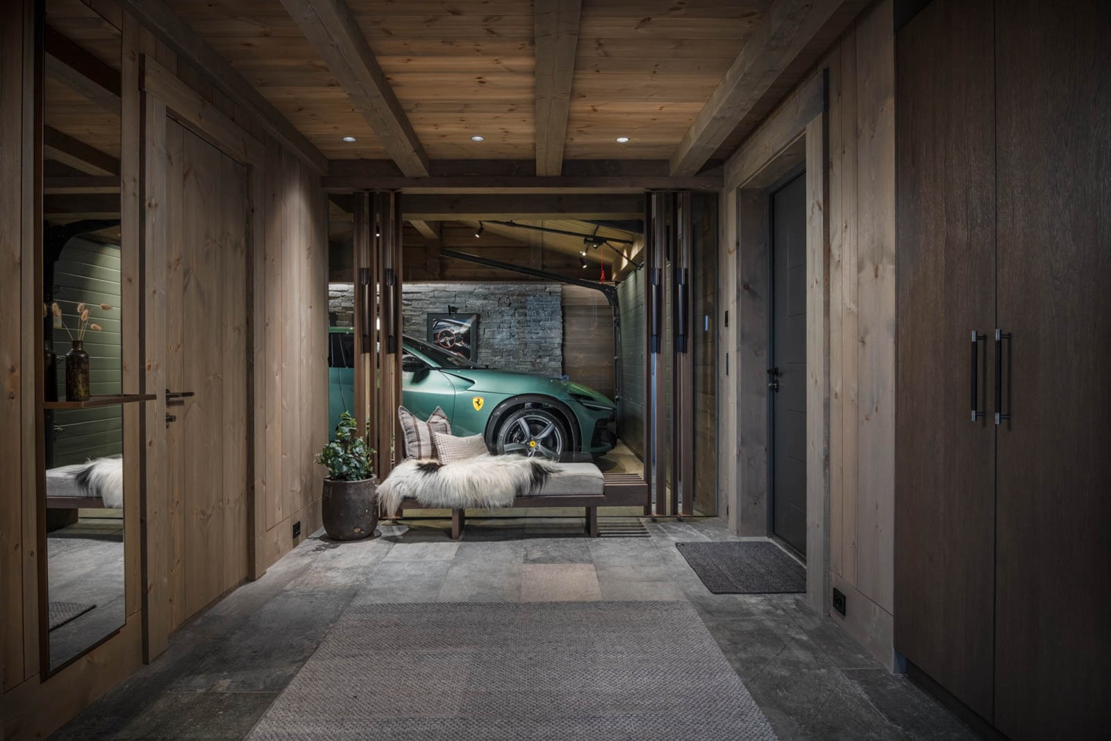 Garasjeinnredning utført til en så høy standard at en fullstor glassvegg visuelt forbinder gangen med garasjen Galleribilde