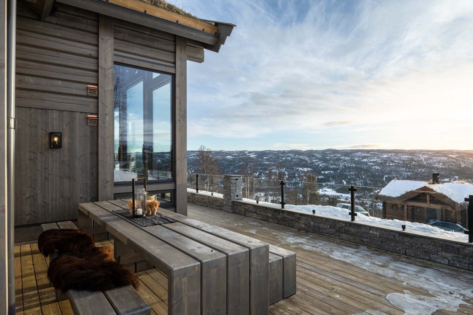 Terrassen, som strekker seg fra hovedstuen, har steiner og glassrekkverk uten ramme, noe som gir fri utsikt og et elegant, minimalistisk uttrykk. Galleribilde