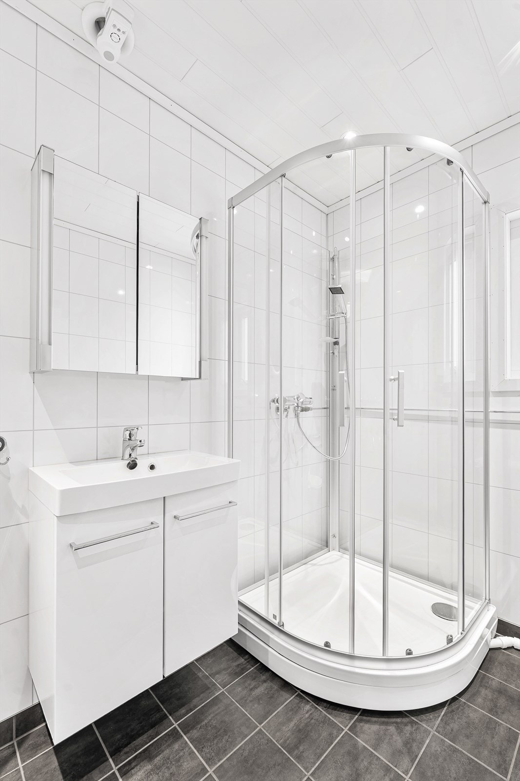 Rommet er innredet med vegghengt toalett, nedfelt servant, speilskap, dusjkabinett og opplegg for vaskemaskin Galleribilde