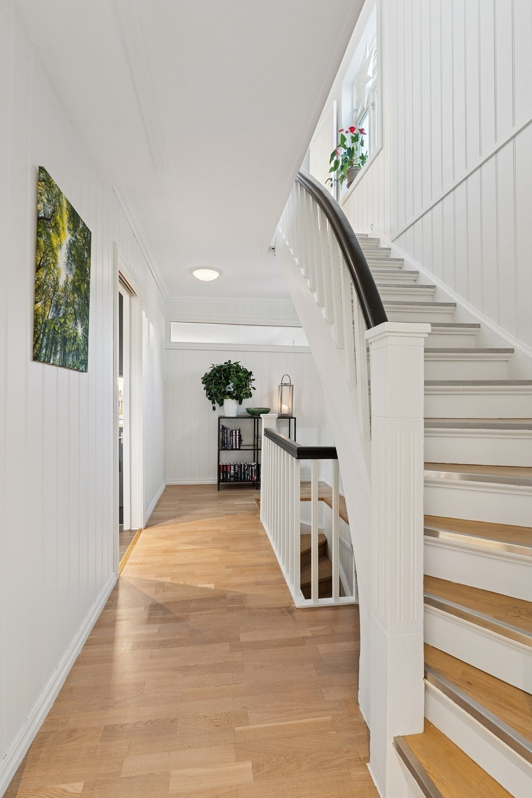 En fin mellomgang og et elegant trapperom binder rommene og etasjene sammen - langsgående vindu vender ut i hovedstuen og slipper ekstra lys inn i denne gangsonen Galleribilde