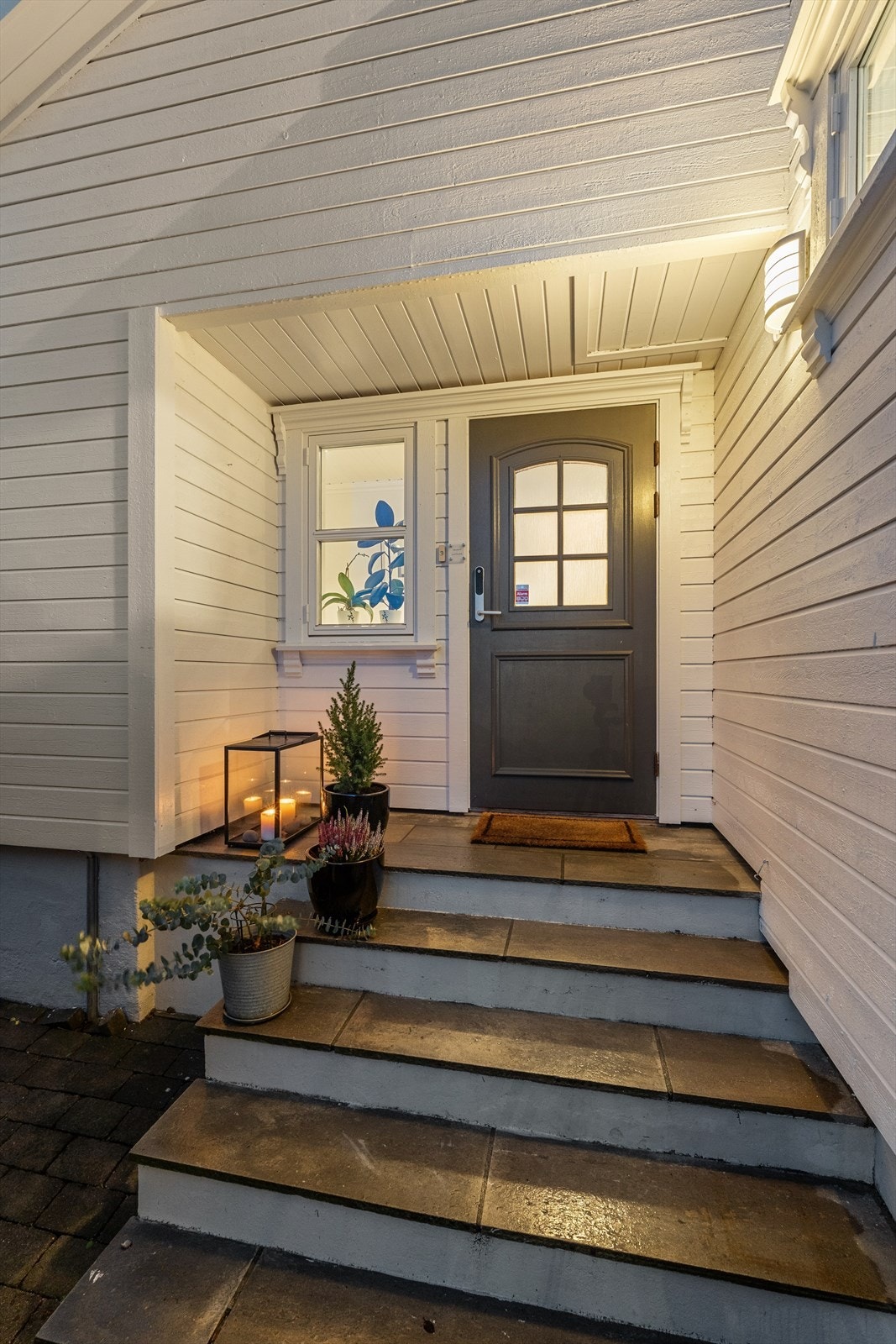 Det overbygde inngangspartiet har skiferlagt trapp og gir et innbydende førsteinntrykk av eiendommen med enkel adkomst fra garasje og gårdsplass Galleribilde