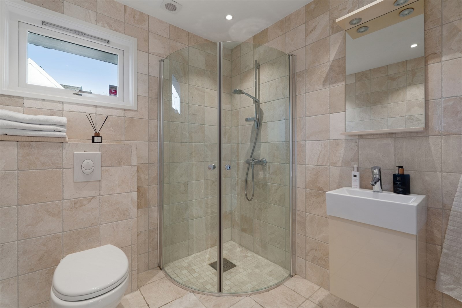 Baderommet i første etasje har fliser på gulv og vegger, samt malt, slett himling med downlights. Galleribilde