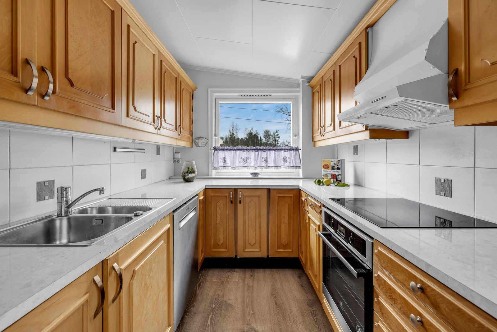 Kjøkken med hvite fliser, vindu og integrerte hvitevarer. Galleribilde