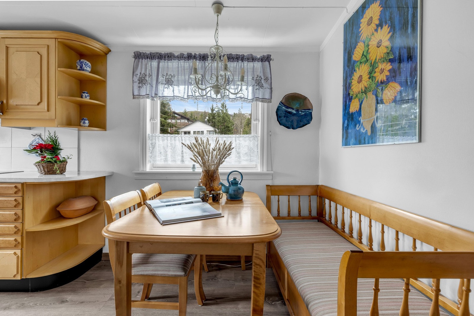 Lyst kjøkken med spiseplass ved vinduet. Hyller og skap gir god oppbevaringsplass. Galleribilde