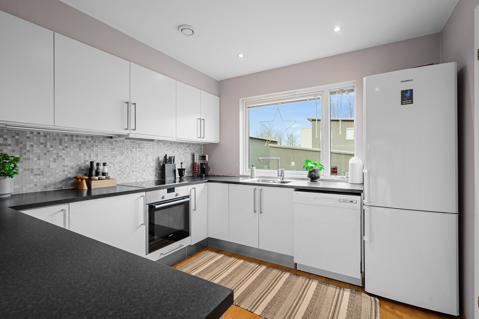 Stilrent, hvitt kjøkken fra HTH med mørk benkeplate. Galleribilde