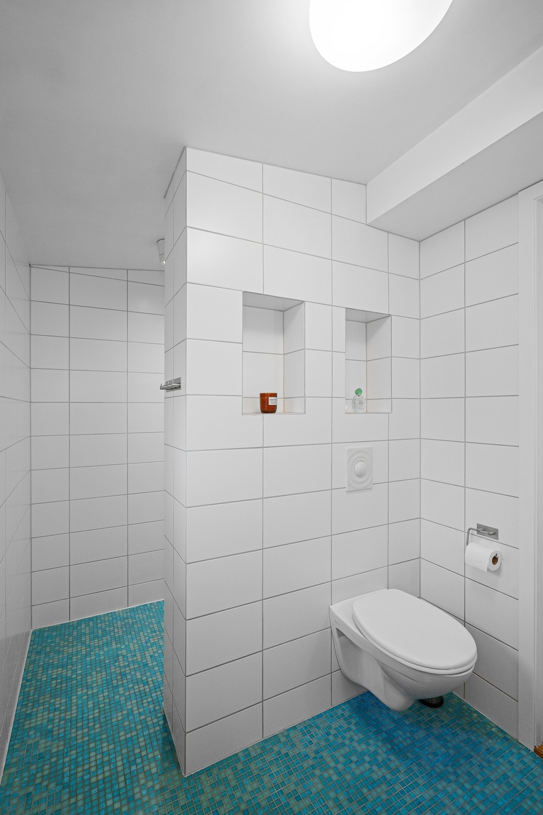 Vegghengt toalett med romslig dusjløsning plassert bak vegg. Galleribilde