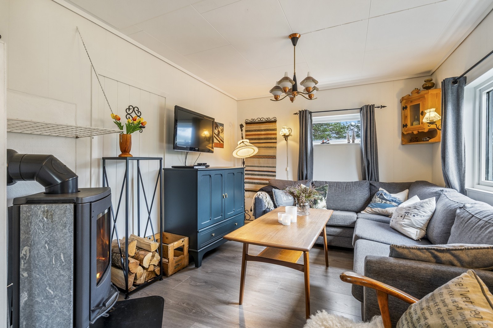 Hytten har en romslig og åpen stue- og kjøkkenløsning med god plass til både sofagruppe og spisebord. Vedovn. Galleribilde