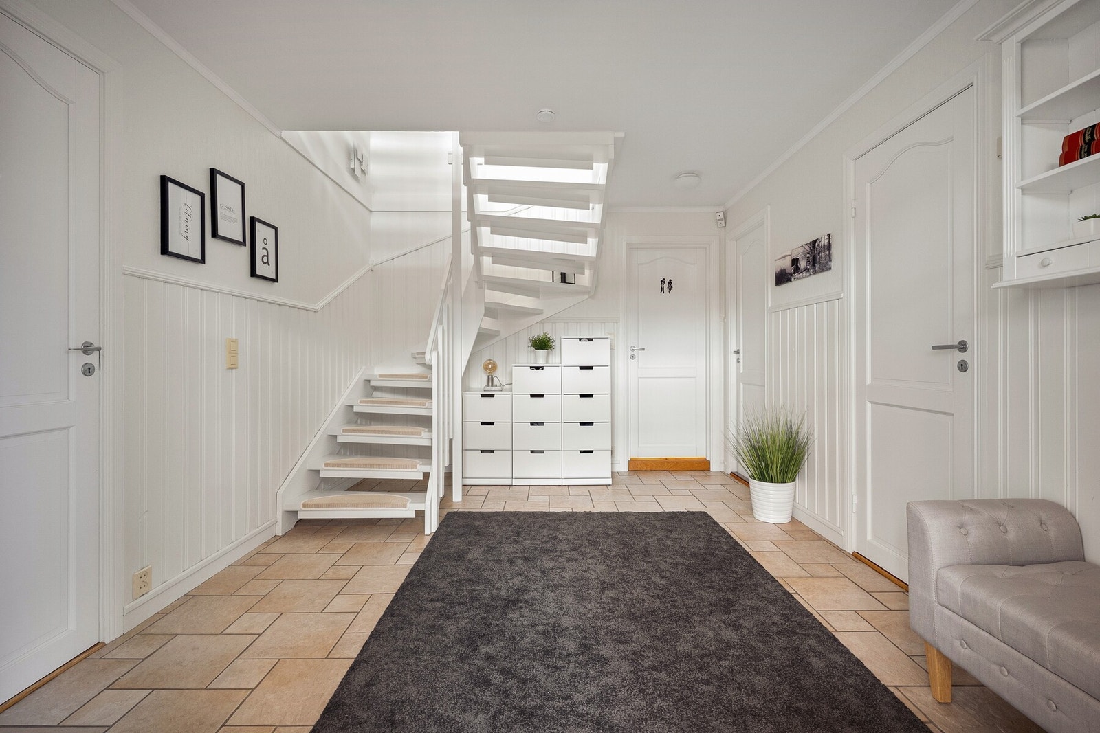 Her er det god plass til garderobeløsninger, og området fungerer som et praktisk bindeledd mellom underetasjens rom og trappen videre opp i boligen. Galleribilde