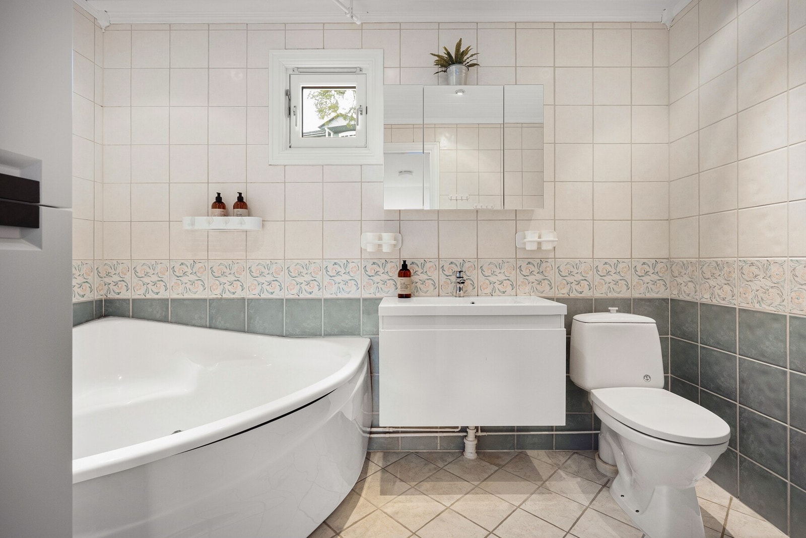 Romslig bad med flislagte overflater som gir et tidløst og praktisk uttrykk. Galleribilde