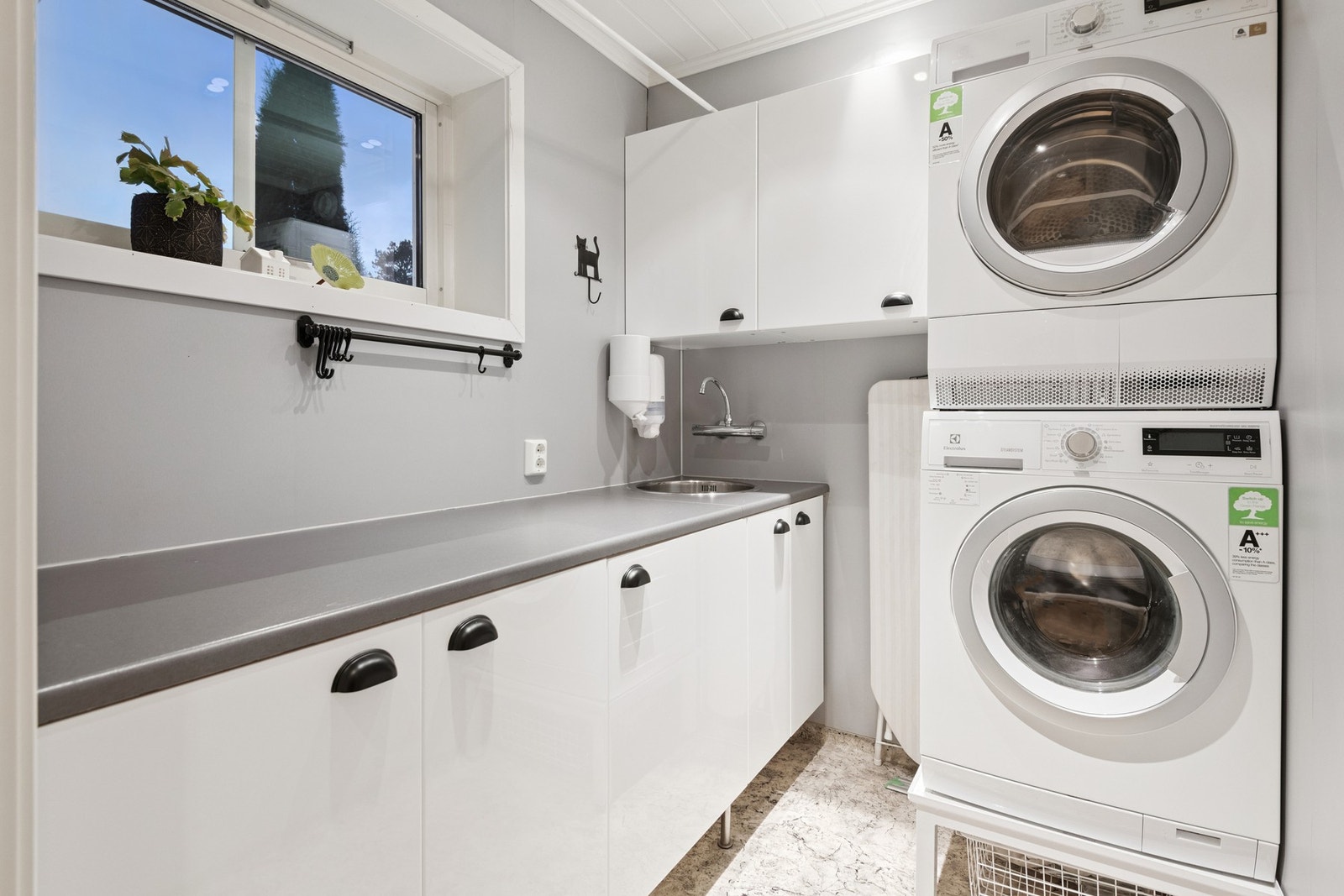 Praktisk vaskerom med belegg på gulv. Det er opplegg for vaskemaskin og utslagsvask. Galleribilde