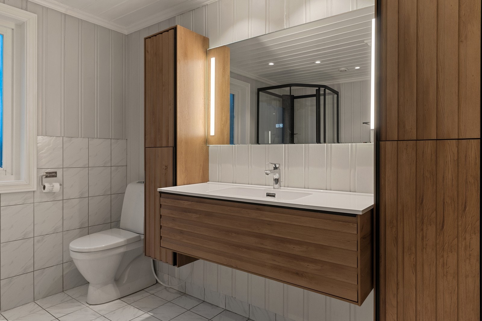 Flislagte overflater og belysning gir et ryddig inntrykk på våtrommet. Galleribilde