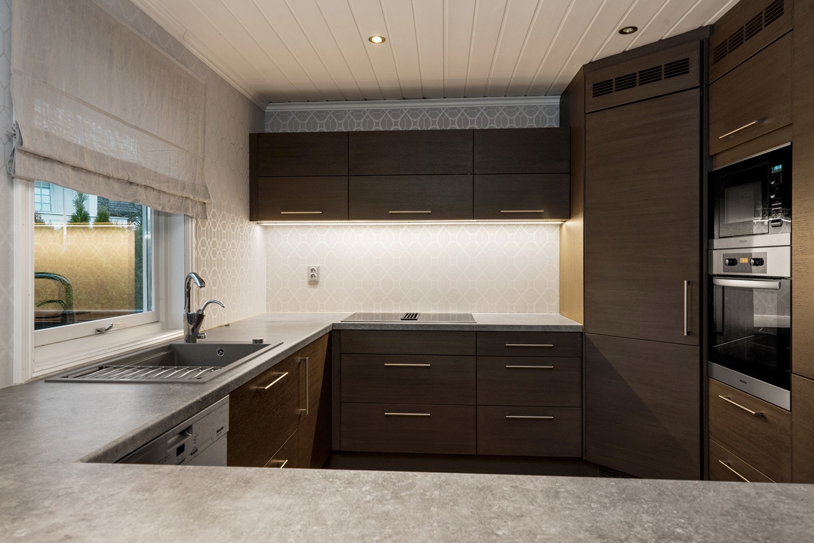 Integrerte Miele-hvitevarer og laminerte benkeplater gir kjøkkenet en effektiv arbeidsflate. Galleribilde