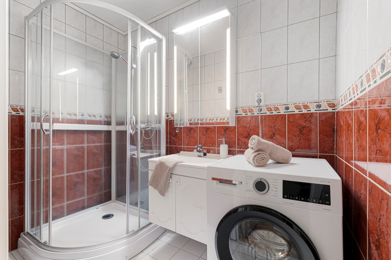 Lyst flislagt bad med opplegg til vaskemaskin. Galleribilde