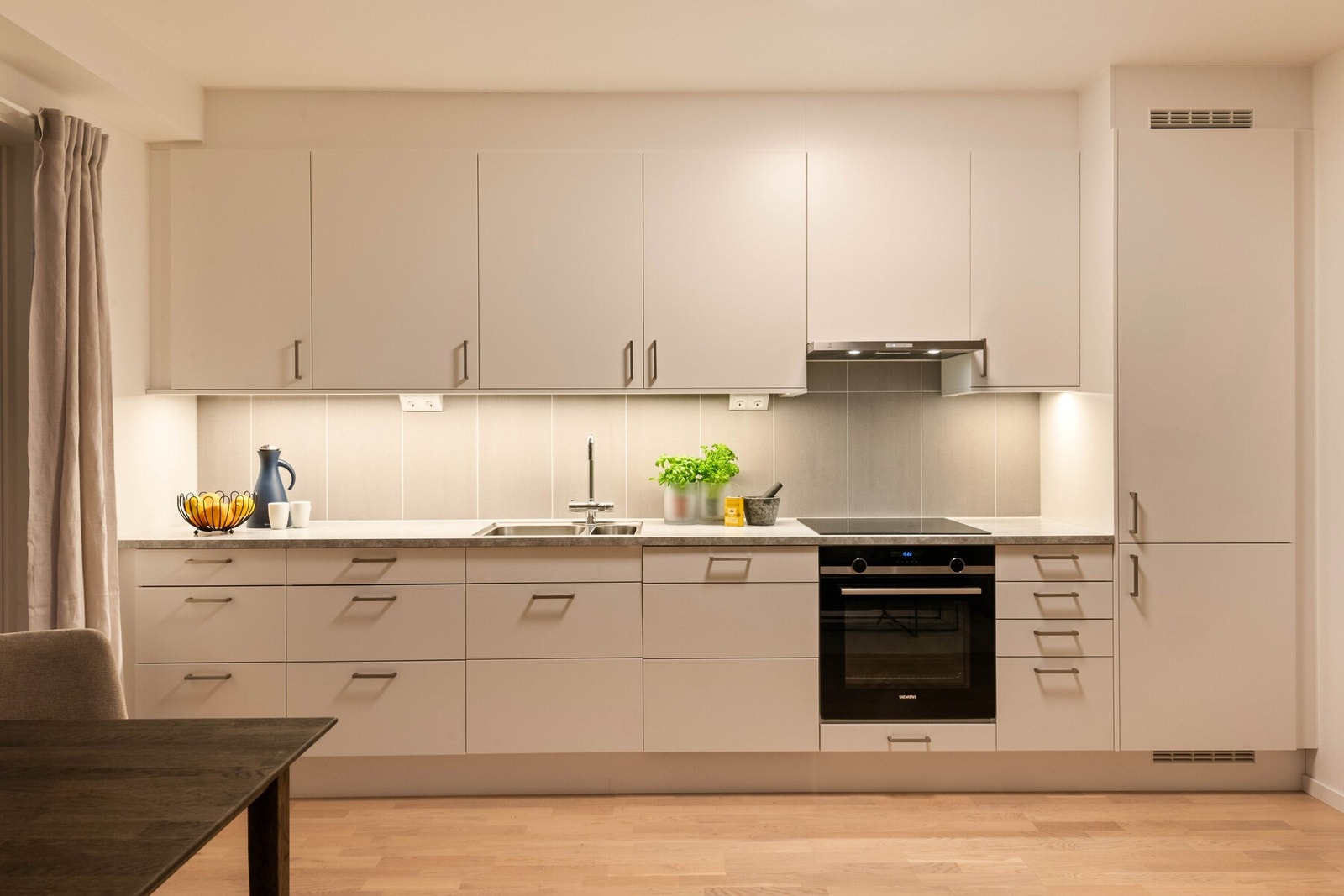 Kjøkkenet har innredning med glatte fronter. Høye overskap. Benkeplaten er av laminat. Det er kjøl/fryseskap, oppvaskmaskin, platetopp, stekeovn, vannstoppsystem og komfyrvakt. Galleribilde