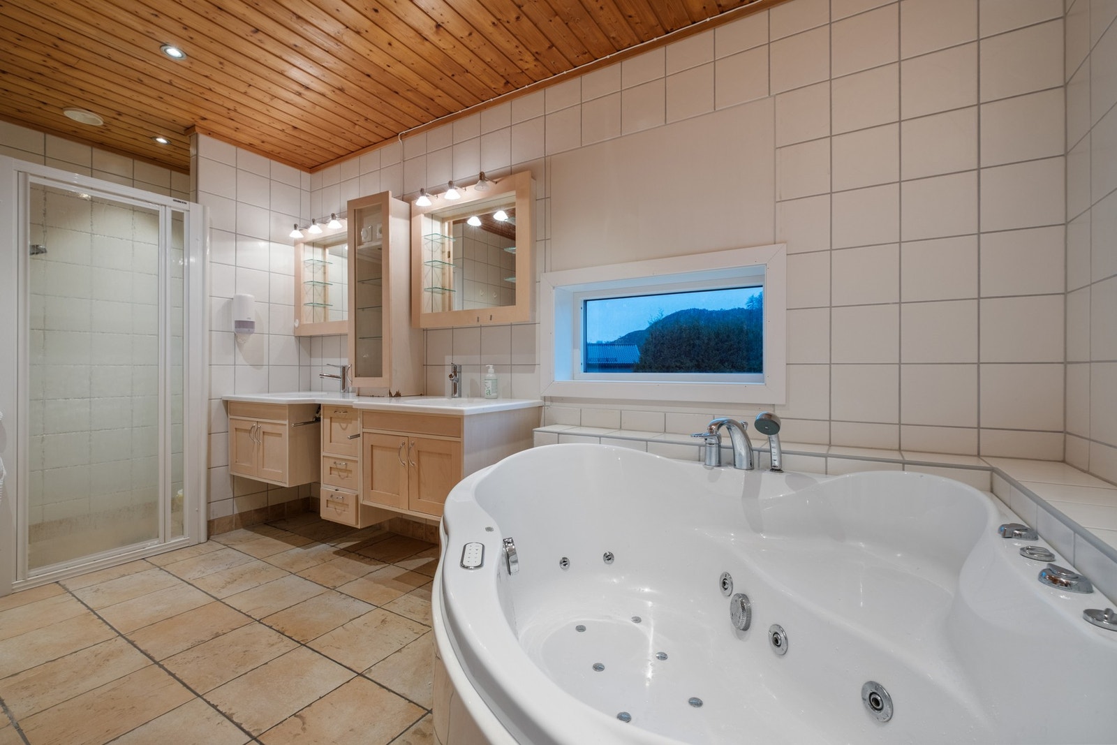 Utstyrt med hjørnebadekar og dobbelt veggmontert servantskap med to servanter. Galleribilde