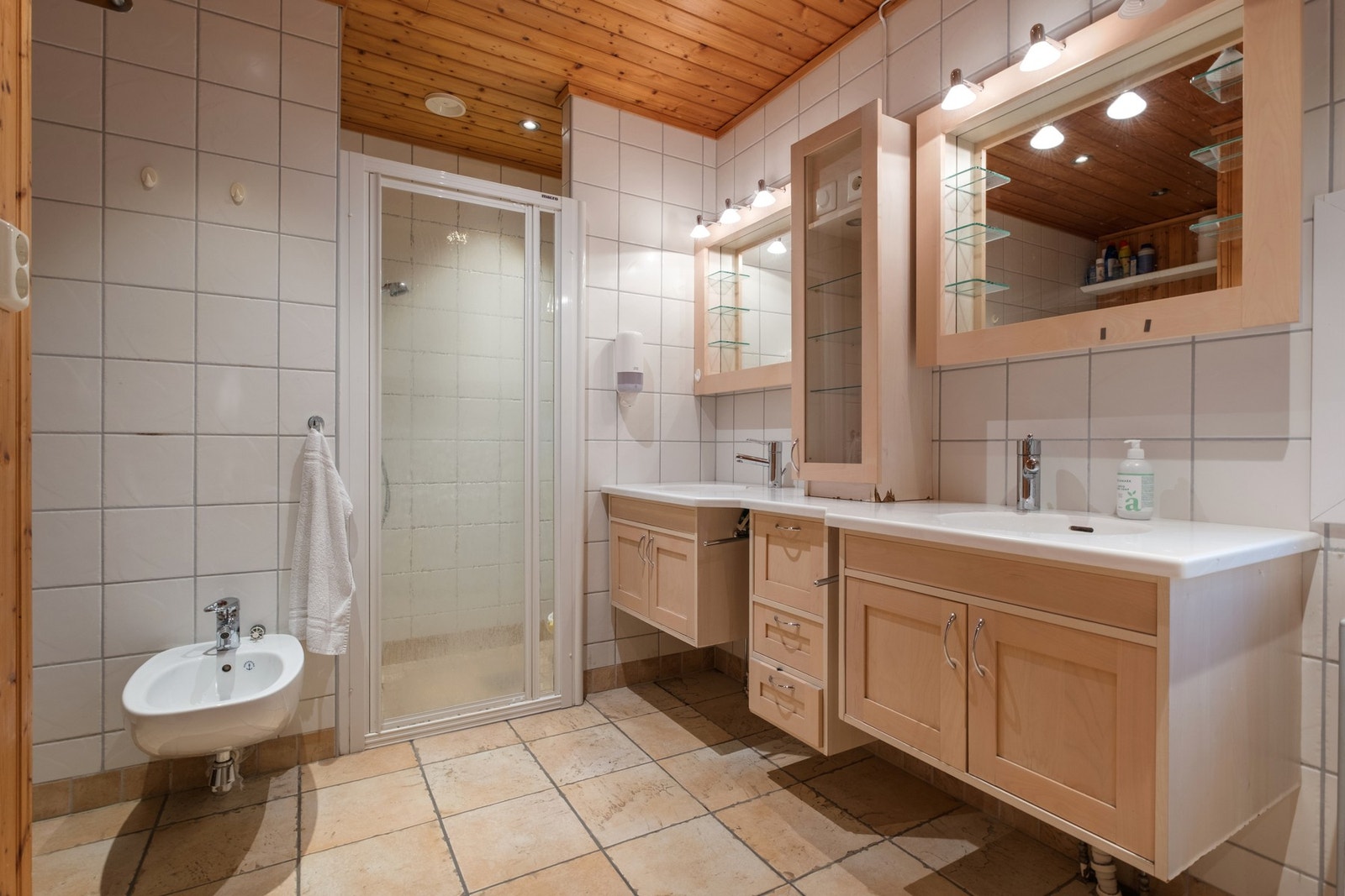 Dusjnisje med dør, bidet, veggmontert toalett og opplegg for vaskemaskin. Galleribilde