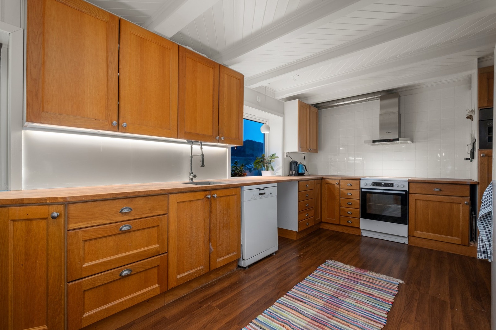 På kjøkkenet er det lagt laminat på gulv, malt overflate på vegger, plate og flis på vegg over benkeplate og malt overflate i himling. Galleribilde