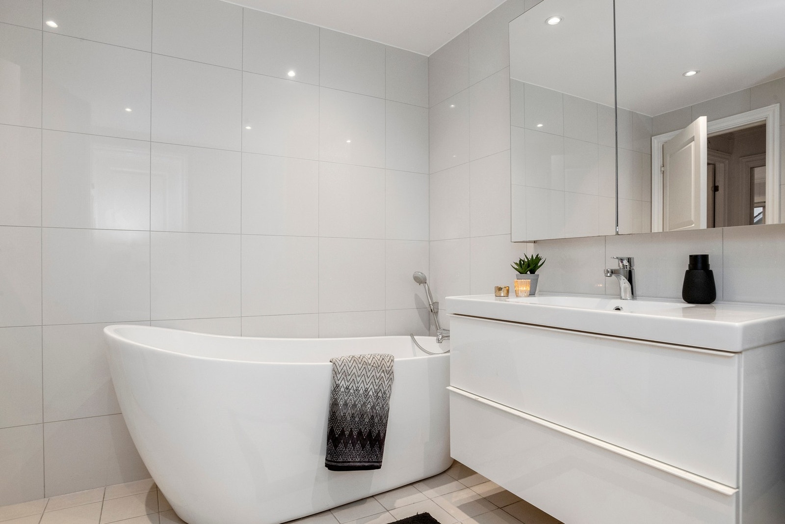 Lekkert og tidsriktig baderom med frittstående designerbadekar, moderne servantløsning og delikate flater - et rom som inviterer til avkobling og hverdagsluksus Galleribilde