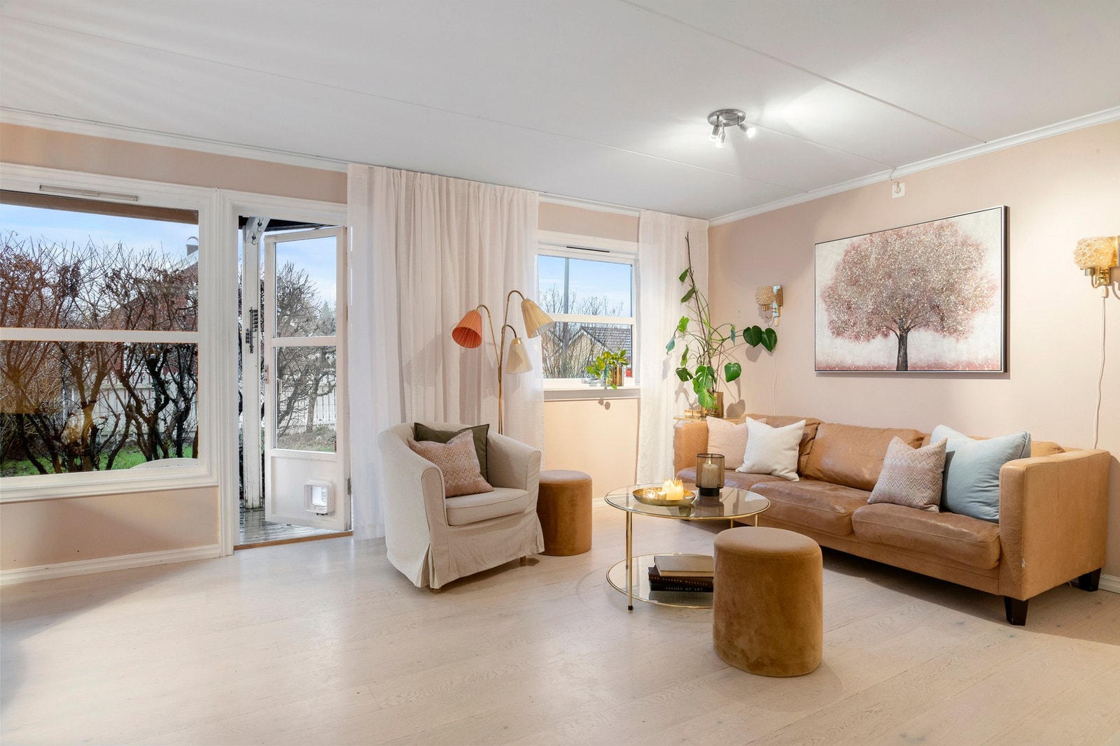 Lys og innbydende stue med delikate farger, store vindusflater og utgang til hagen - et lunt og behagelig rom for avslapning og sosialt samvær. Galleribilde