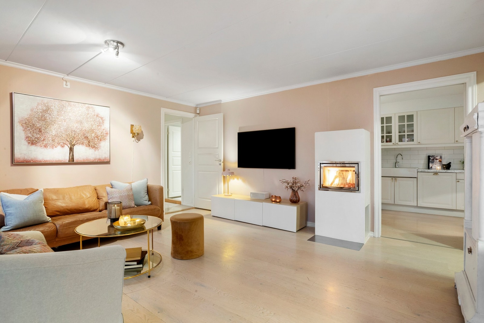 Lun og innbydende stue med peis, delikate fargetoner og harmonisk flyt videre inn til kjøkkenet - et perfekt rom for både hverdagskos og sosiale kvelder. Galleribilde