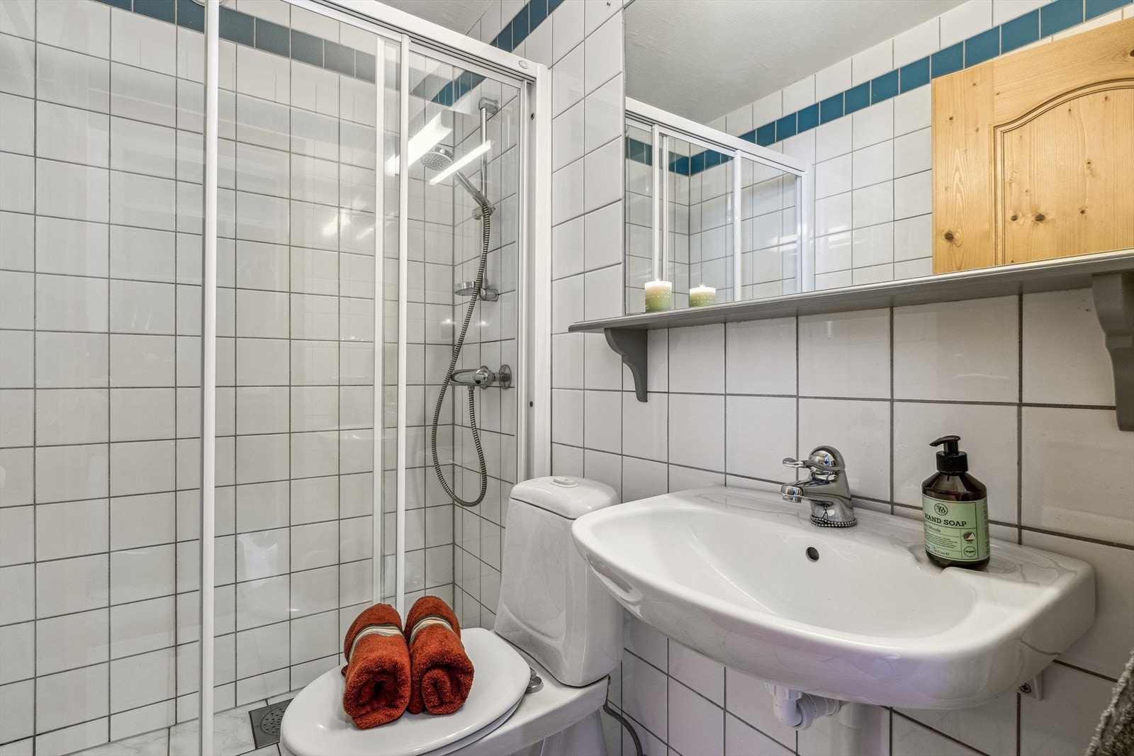 Badet har fliser på gulv og vegg, toalett, servant og dusjdører. Galleribilde