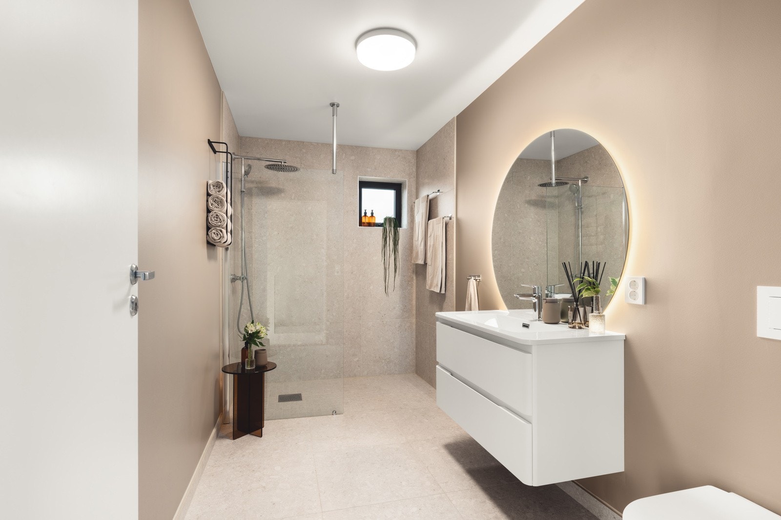 Badet fremstår som moderne og stilrent med flislagt gulv og fliser i dusjsonen, kombinert med lyse vegger som skaper en varm og innbydende preg. Galleribilde