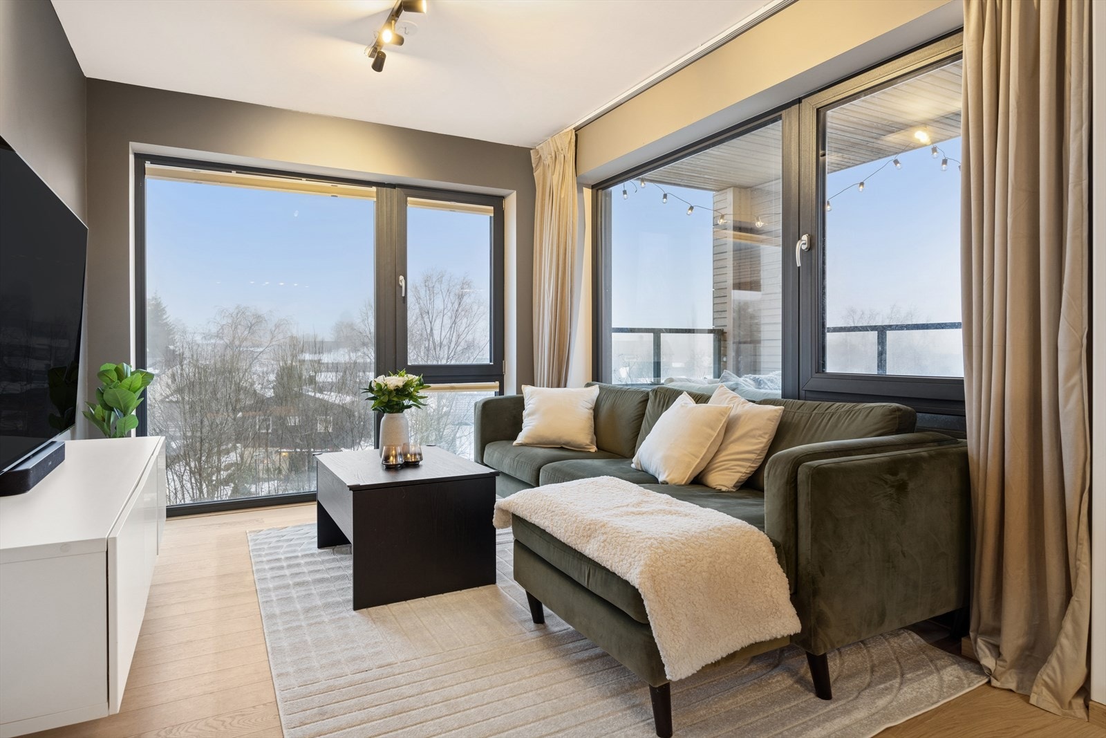 Lys stue med plass til sofagruppe og med utsikt gjennom flere vinduer. Galleribilde