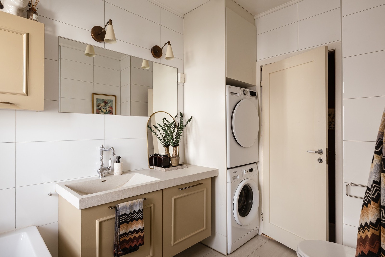 Badet er innredet med dusjhjørne, vegghengt toalett, badekar samt servantseksjon med skap og speil. Galleribilde